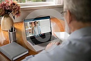 Rear view senior man watching webinar, learning language online