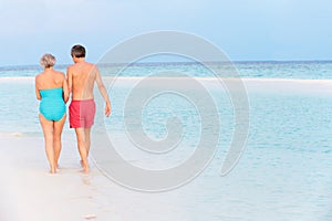 Rear View Of Senior Romantic Couple Walking In Tropical Sea