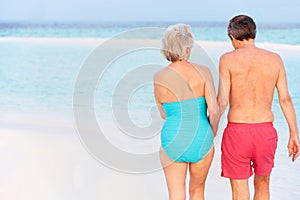 Rear View Of Senior Romantic Couple Walking In Tropical Sea