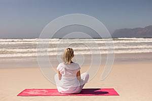 Rear view Senior woman meditating at beach on a sunny day