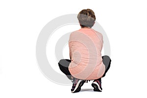 rear view of a senior woman squatting on white