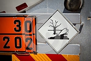 Rear view of service and refuelling truck on an airport with HAZARDOUS TO AQUATIC ENVIRONMENT warning sign.