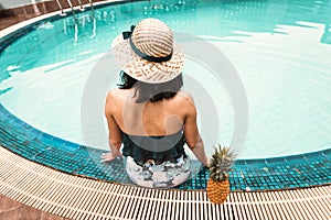 Rear View of Sexy Woman in Swimsuit Relaxing in Swimming Pool, Beautiful Woman Wearing Straw Hat and Relax on The Edge of Poolside