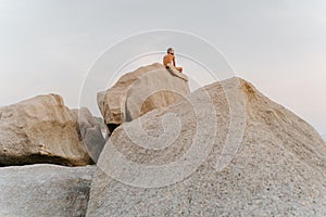 Rear view of a shirtless man seeking tranquility while sitting on a rock formation in Koh Tao, Thailand