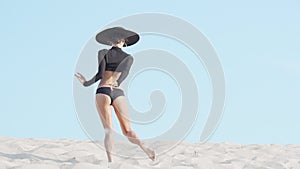 Rear view shot of a fit athletic female dancer performing outdoors on sand
