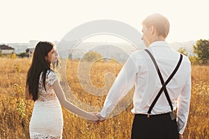 A couple enjoying a walk, holding hands, with the city on the ho