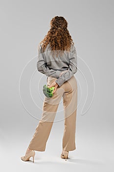 Rear view of slender woman with broccoli behind her back