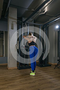 Rear view of a slender woman doing exercises for the buttocks. Beautiful sportive young woman is engaged in the gym