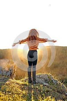 Rear View On Slender Young Caucasian Woman With Red Curly Hair Raising Hands In Mountains