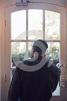 Rear View Of Small Business Owner Standing By Shop Door Making Call On Mobile Phone