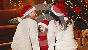 Rear view of small family enjoying Christmas tree