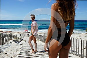 Rear view of a smiling attractive young man is turned back to makes acquaintance with the sexy young woman on the beach.