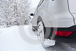 Rear view of snow tires of car driving over snowdrift, winter season