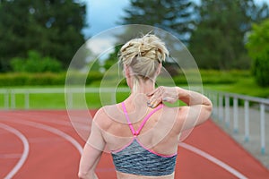 Rear view of sprinter massaging her own neck