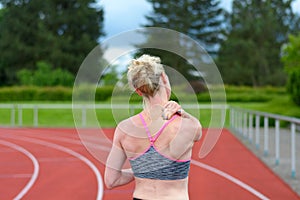 Rear view of sprinter massaging her own neck