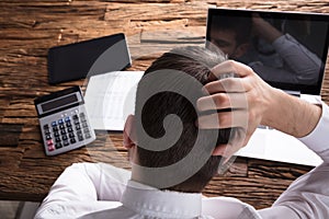 Rear View Of A Stressed Businessman Scratching Head photo