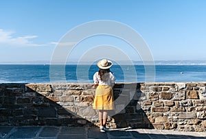 Rear view of stylish young woman standing on viewpoint over sea in Piran, Slovenia.