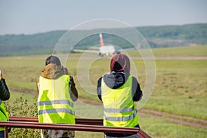 Rear view of a team of spotters standing in front of an airplane