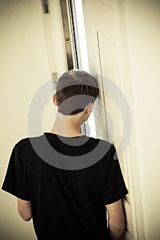 Rear View of Teenage Boy Leaning Head Against Wall