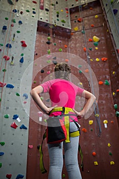 Rear view of teenage girl standing with hands on hip