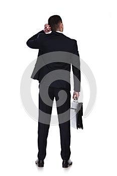 Rear view of thinking businessman holding briefcase