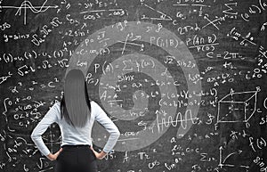 Rear view of a thoughtful woman who tries to solve math problems. photo