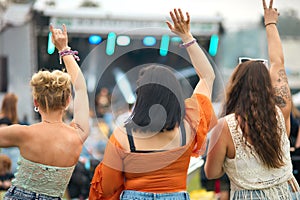 Rear View Of Three Female Friends Dancing At Summer Music Festival 