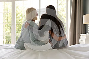 Rear view three generations of women hugging, enjoying tender moment