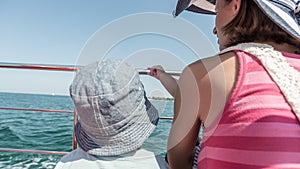 Rear view of toddler son with his mother on boat deck