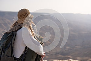 Rear view of tourist blonde woman with backpack and hat in viewpoint landscape of wilderness Canyon Wadi Mujib in Jordan photo