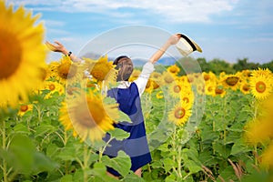 Rear view of travel lifestyle women with hands up hat in sunflower field, in summer day and happy vocations.