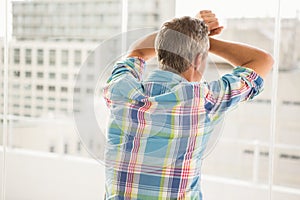 Rear view of troubled casual businessman leaning against window