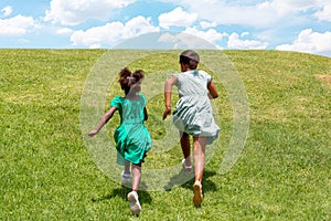 Rear view of two African girls running in a grass field