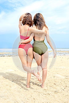 Rear view of two asian sexy girl in bikini and swimsuit on the beach