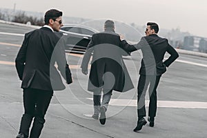 rear view of two bodyguards going with businessman