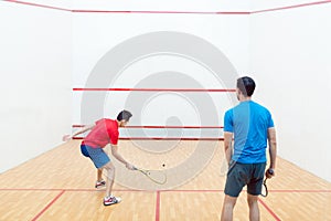 Rear view of two competitive young men playing squash game