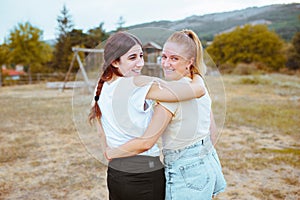 Rear view of two friends smiling and hugging each other in the countryside. Best friend love and friendship concept