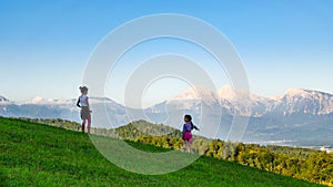 Rear view of two kid girls standing in a mountain meadow