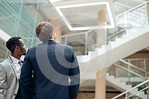 Rear view of two multiracial businessman looking at new empty office space