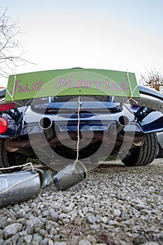 Rear view of a Vintage wedding car with just married sign and cans attached