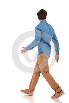 Rear view of a walking casual man looking to side