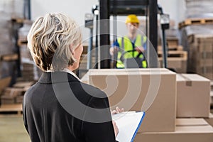 Rear view of warehouse manager in front of her colleague