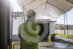 Rear view of warehouse worker waiting on loading dock for loading vehicle, delivery truck.
