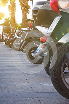 Rear view of the wheels of parked mopeds for sale, rental