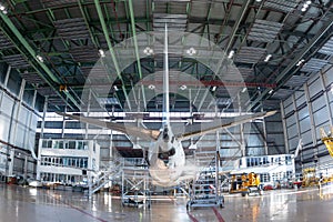 Rear view of a white passenger jetliner in the aviation hangar. Aircraft under maintenance