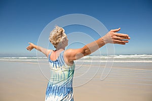 Rear view of woman with arms outstretched standing against clear sky