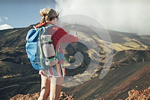 Rear view of woman backpacker taking photo with smart phone