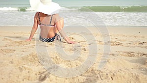 Rear view of woman in a bikini and sun hat while sunbathing on sea sand paradise beach
