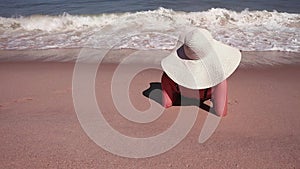 Rear view of woman in a bikini and white sun hat while sunbathing on sea sand paradise beach