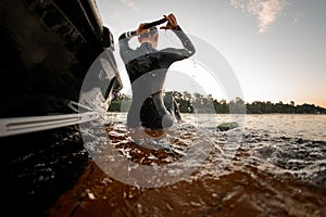 rear view of woman in black wetsuit in the water near the boat